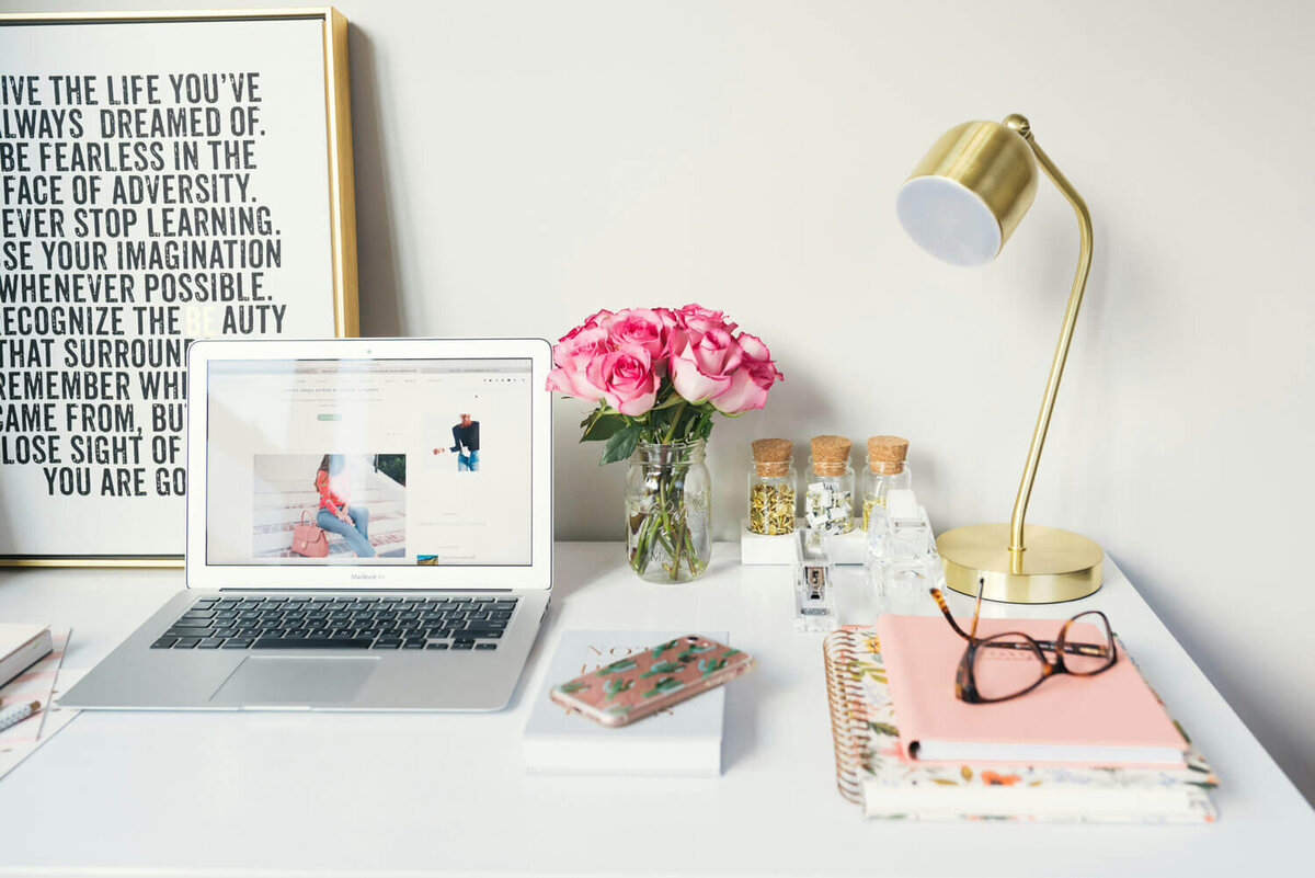 Desk of a real estate agent -  computer, vase of flowers, glasses, and a notebook