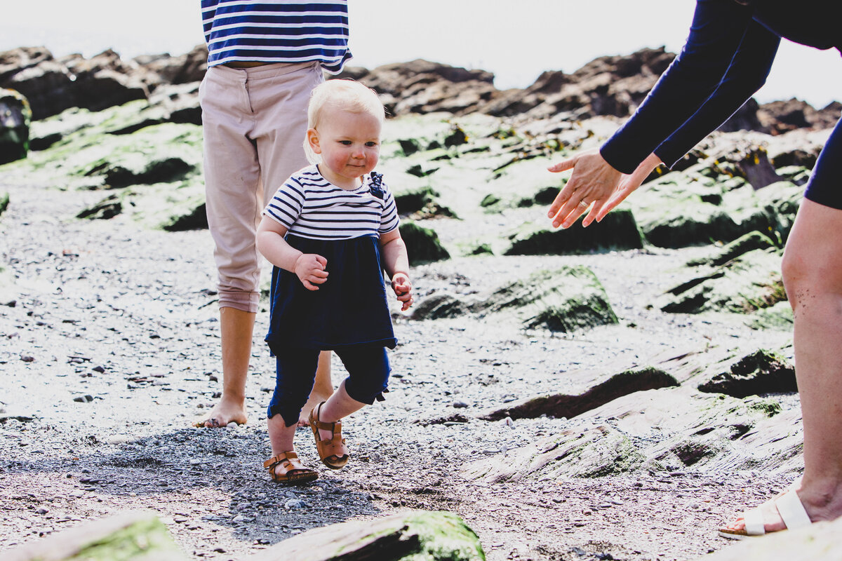 A toddler walking towards open arms captured by Devon Wedding Photographer Liberty Pearl Photography