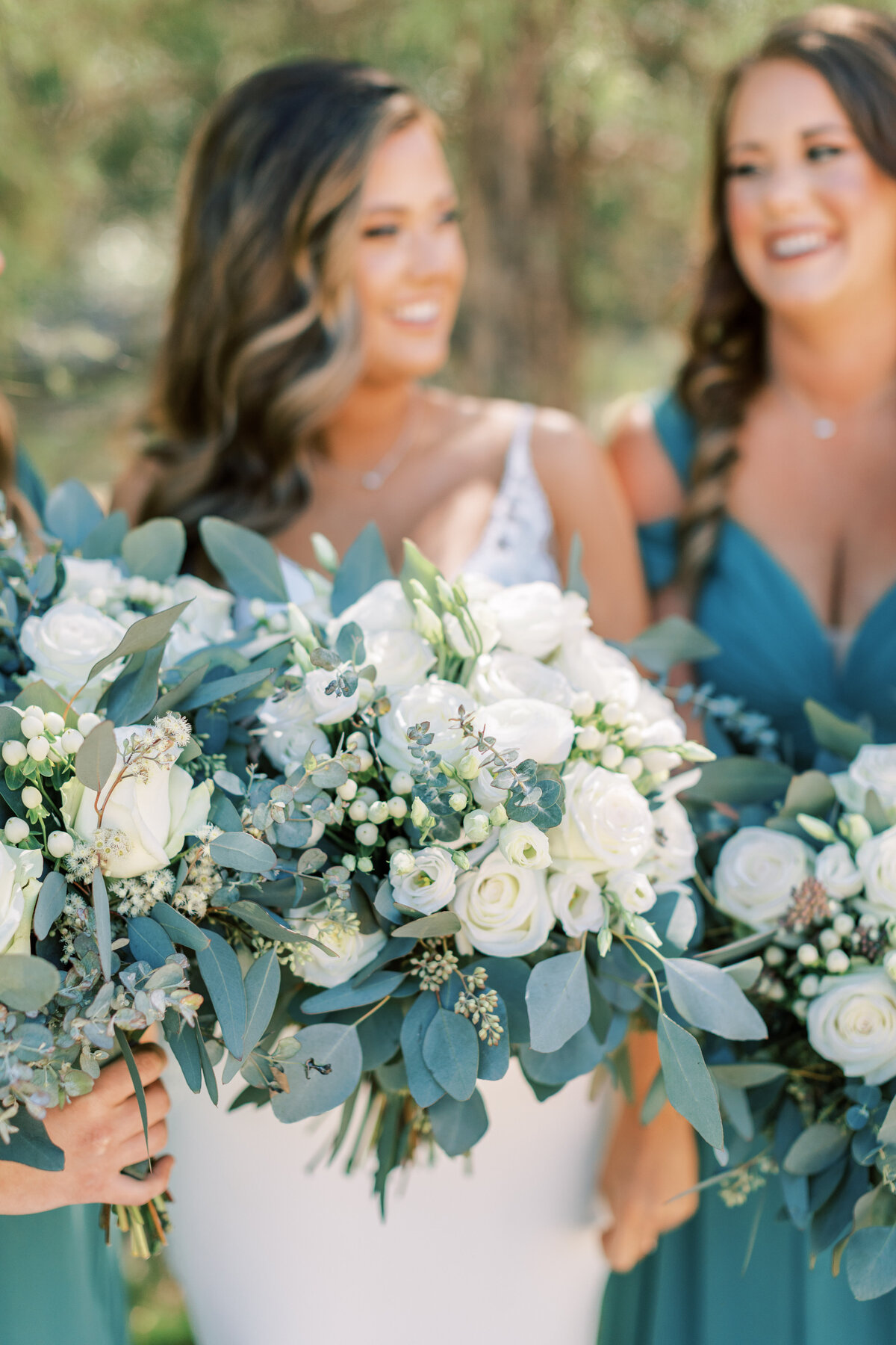 A bride and the bridesmaids hold out their bouquets.