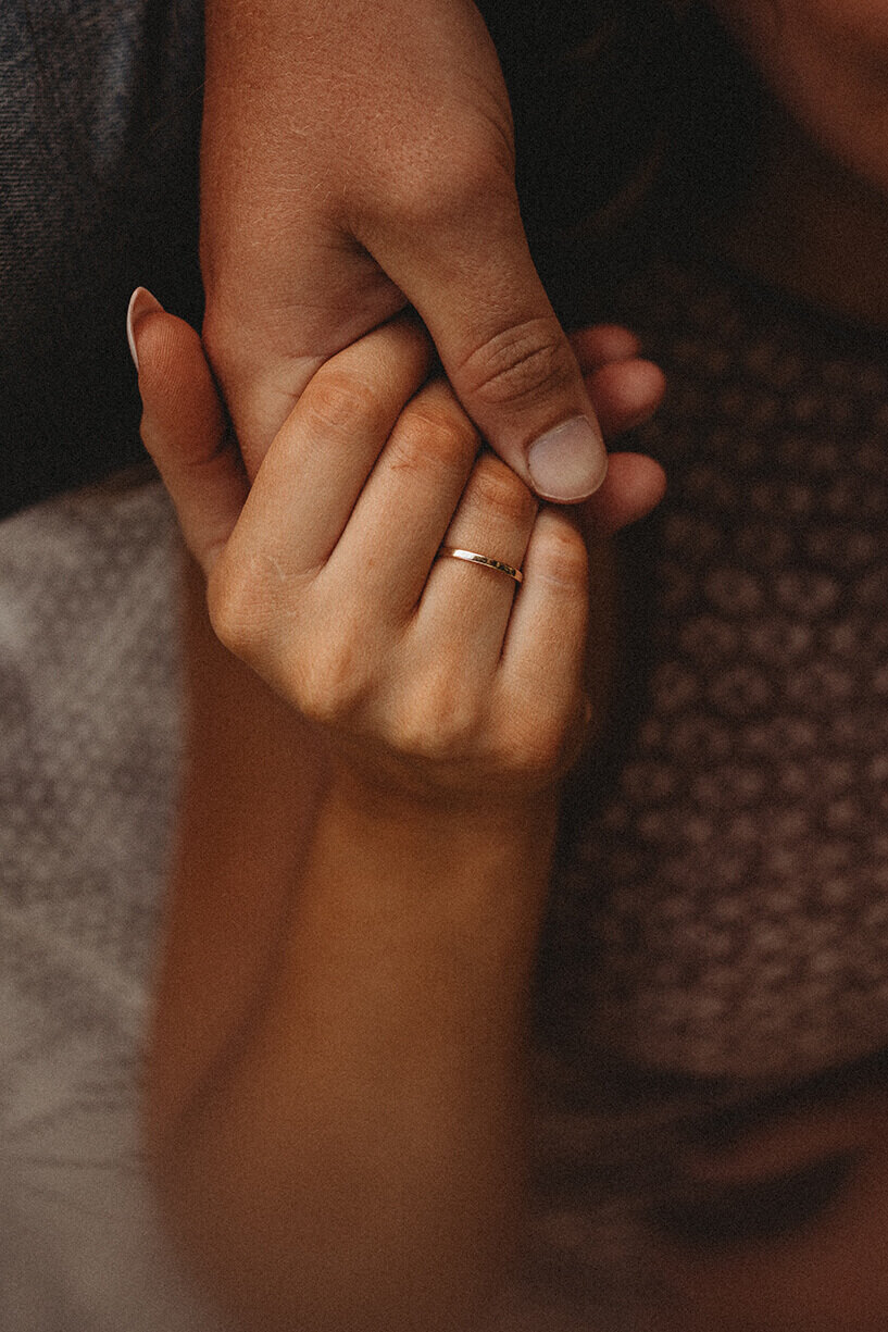 A close up shot of a  husband and wife gently holding hands