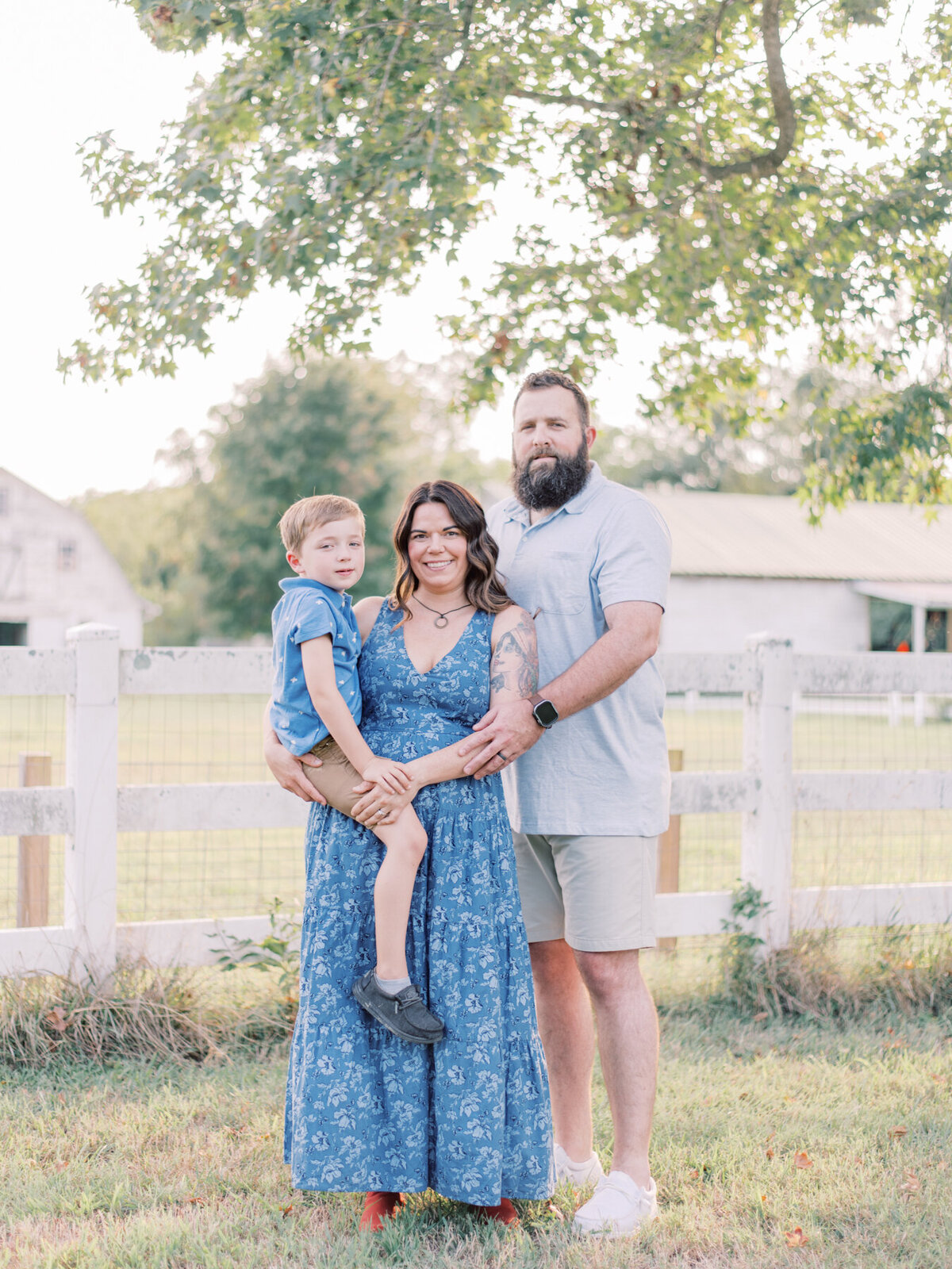 Mom and Dad holding their young son in front of Richmond barn.