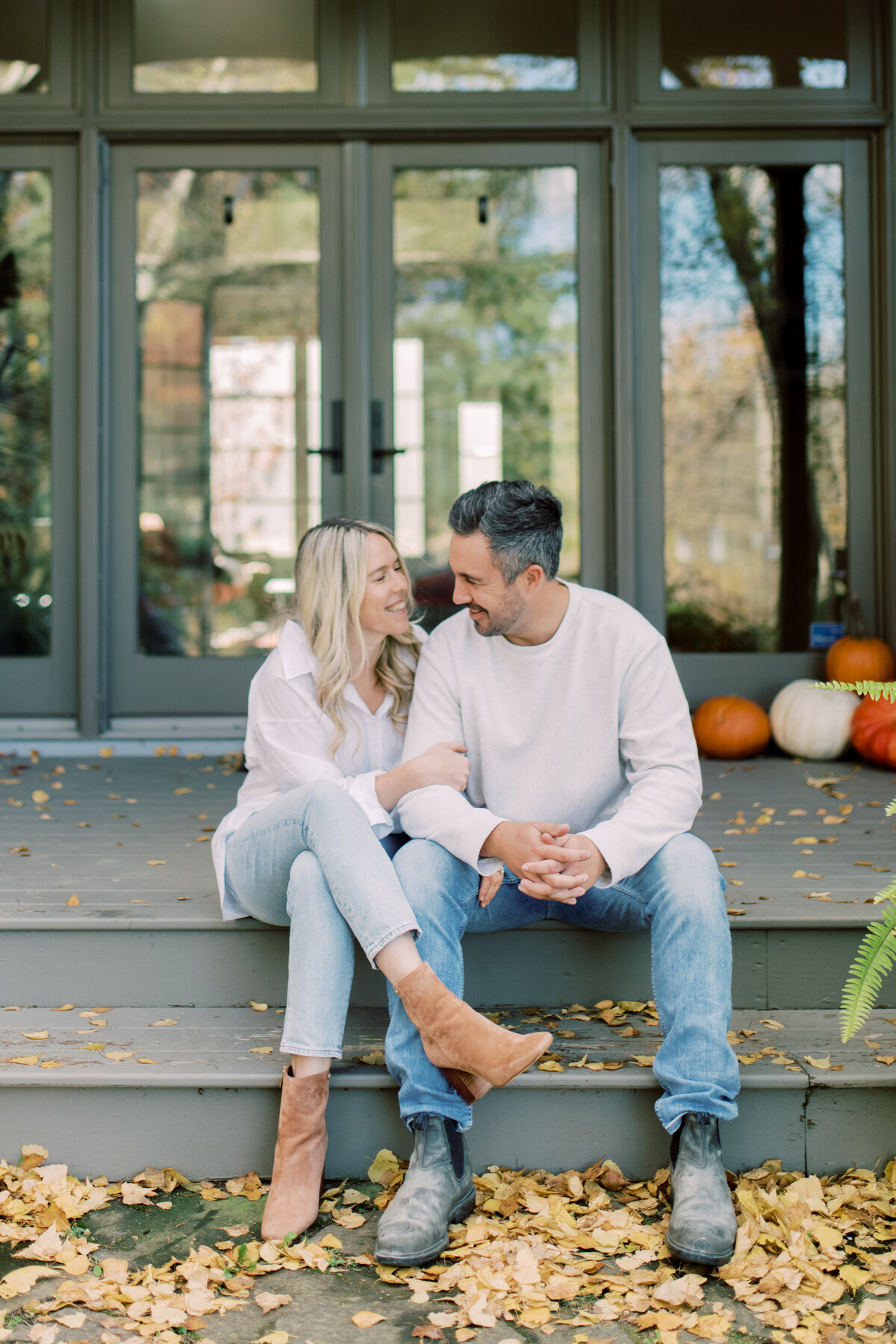 Couple sitting on a porch in Elora ON, with pumpkins in the background