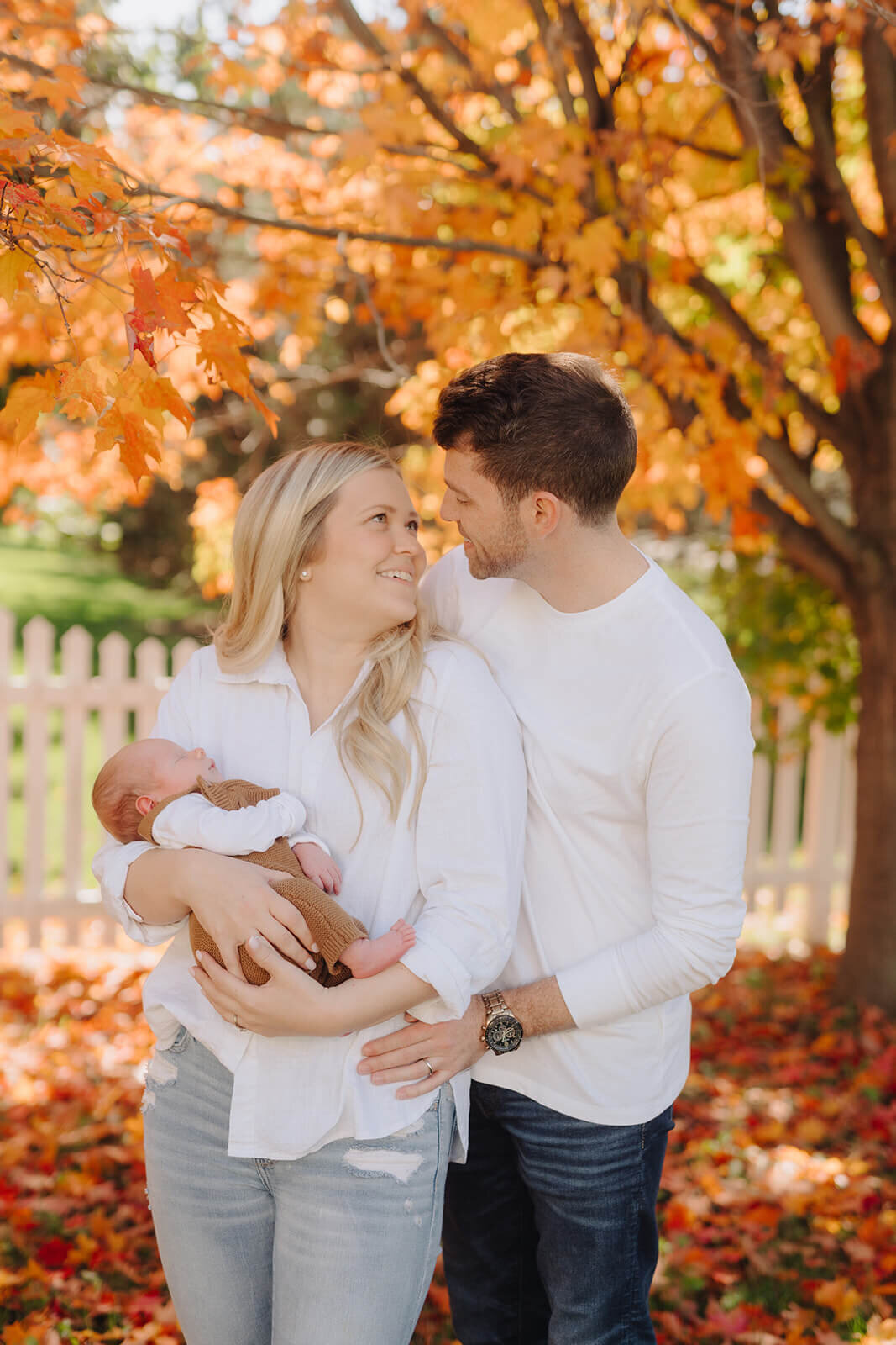 Couple looking at each other holding a newborn baby at newborn photoshoot at Finger Lakes, NY