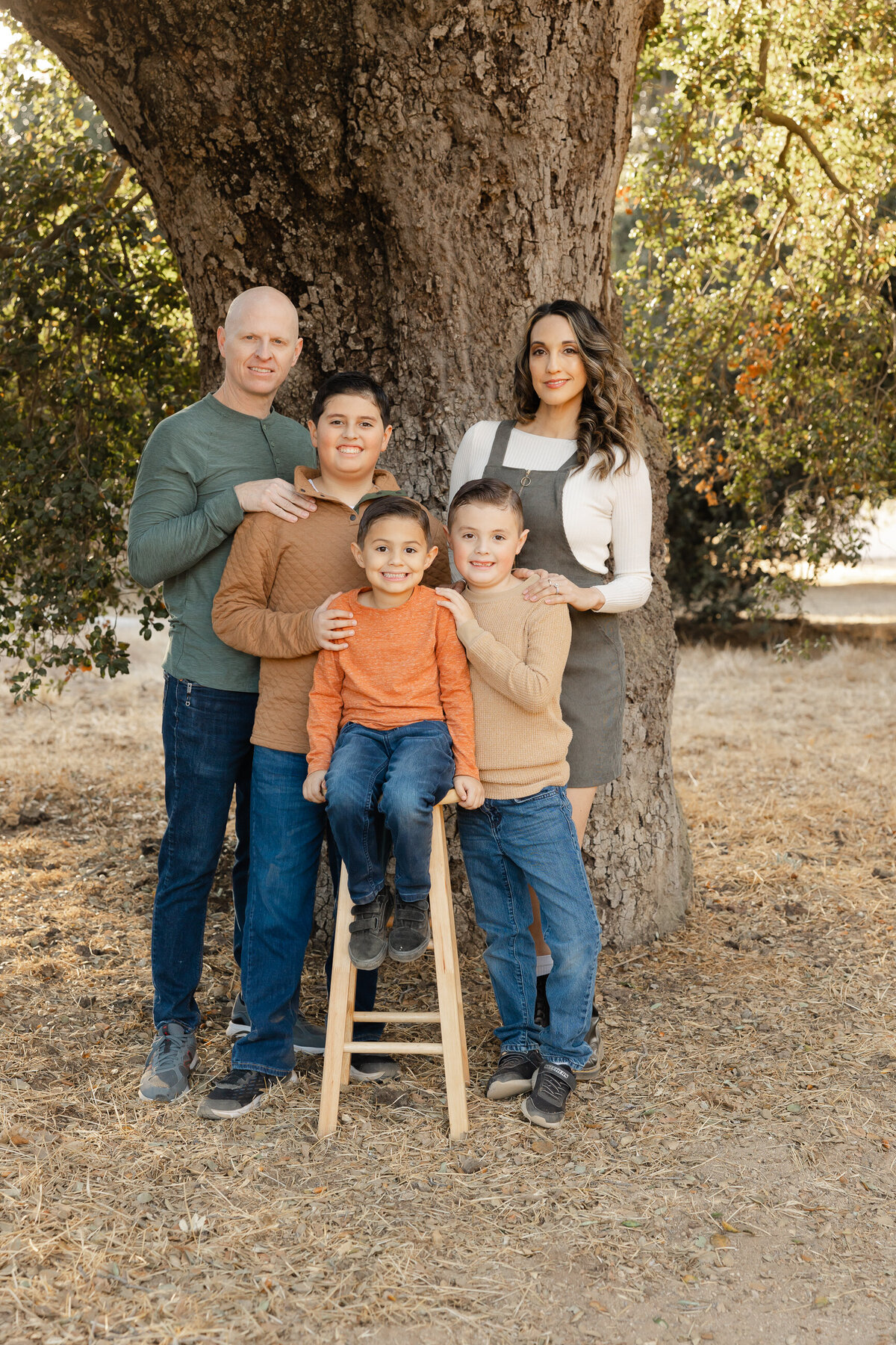 Family grouped closely together outdoors, sharing warm smiles. Photographed by Yucaipa family photographer Kaitlyn Dawn Photography.
