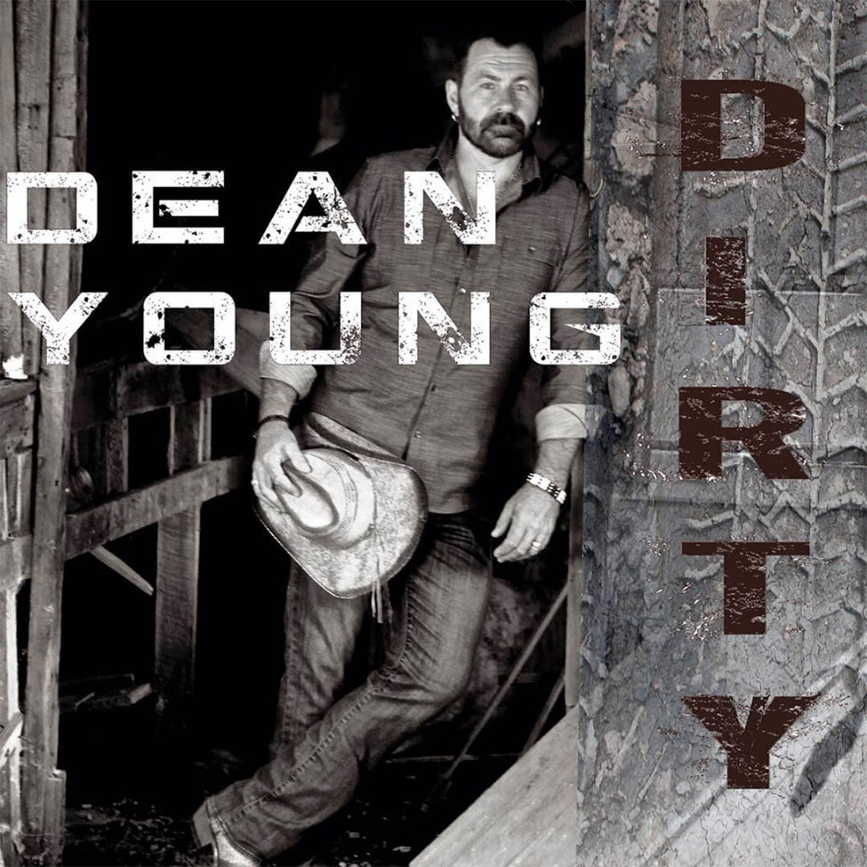 Single Cover Title Dirty Artist Dean Young leaning against doorframe of barn holding cowboy hat by his hip black and white Title Dirty in red
