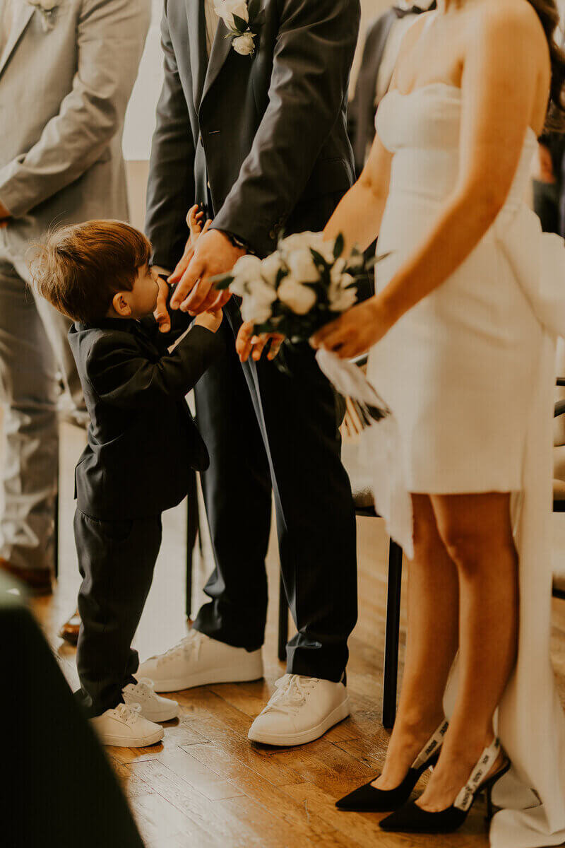 Petit garçon sollicitant les bras de son papa, le marié pendant la cérémonie à la mairie, immortalisé pendant le shooting photo mariage.