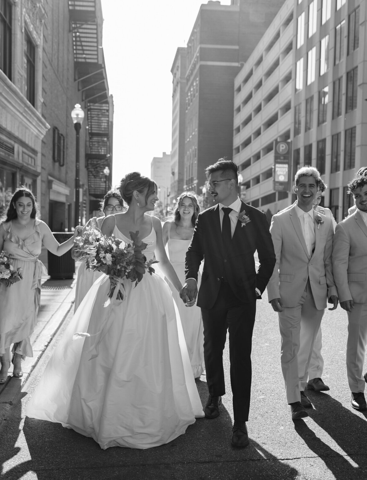 A bride, groom, & wedding party laugh in the streets of Detroit, Michigan