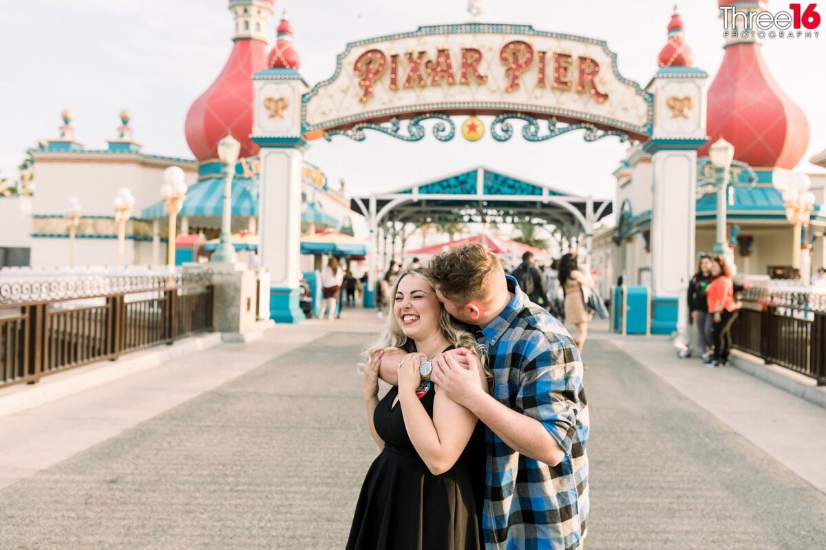 Groom to be whispers into his Bride's ear at Disneyland California Adventure in front of Pixar Pier.