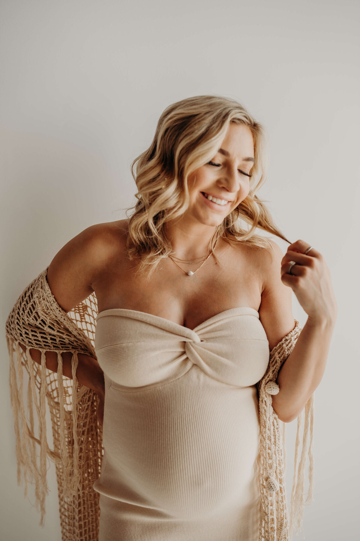 individual portrait of pregnant blonde in strapless cream colored dress and boho kimono