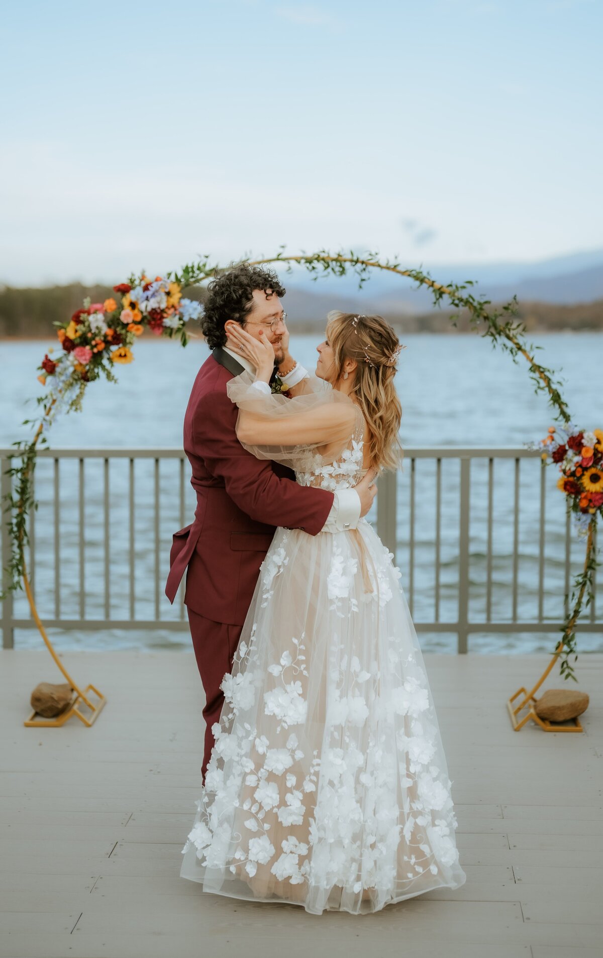 Bride and groom kissing under floral arch.