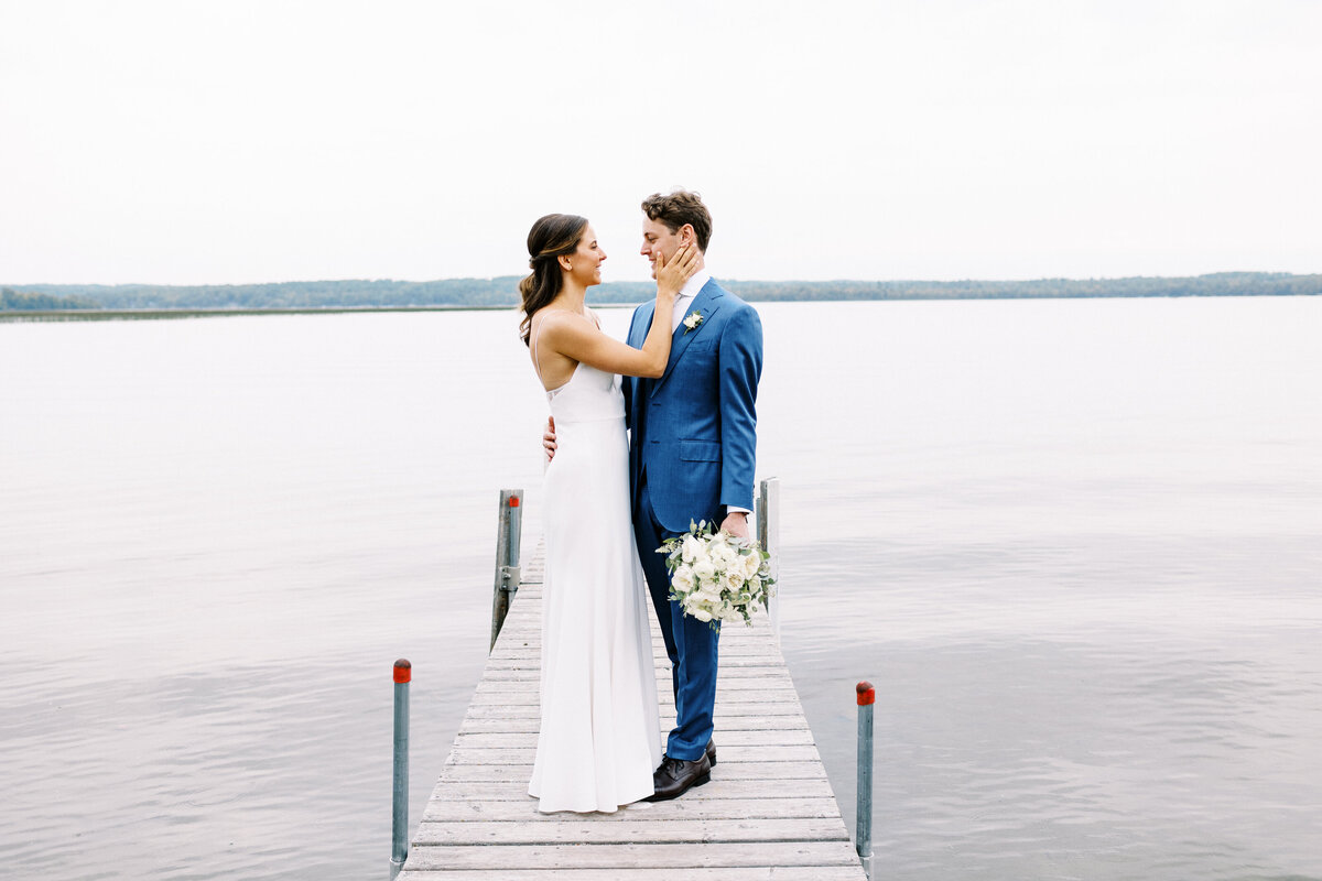 Bride and groom standing on the dock  smiling at Madden's On Gull Lake