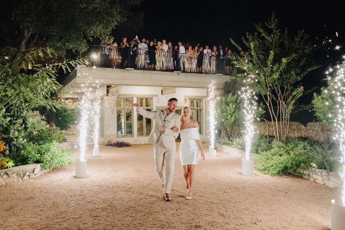 Bride and groom walking through six cold spark machines at their wedding send off