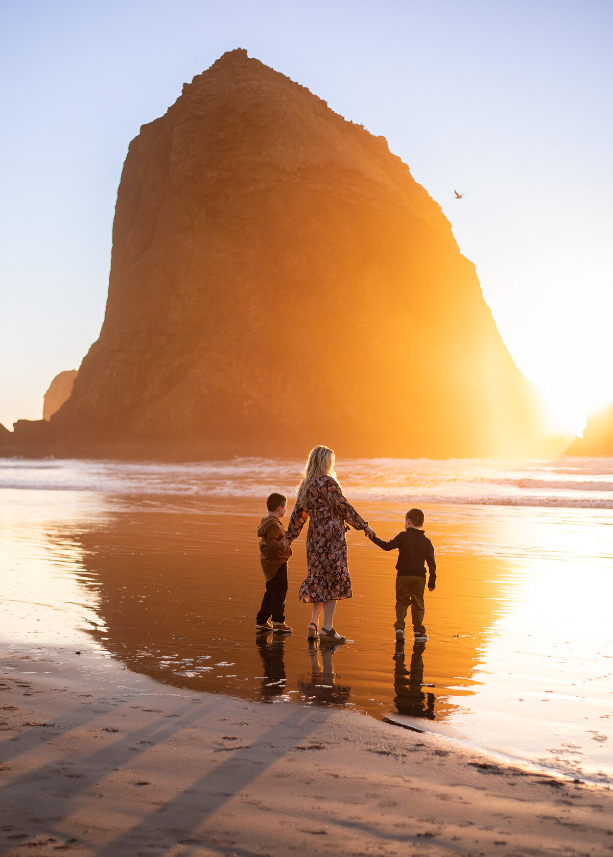 Portland Oregon family photographer takes photo of family in front of Haystack rock at sunset at Cannon Beach.