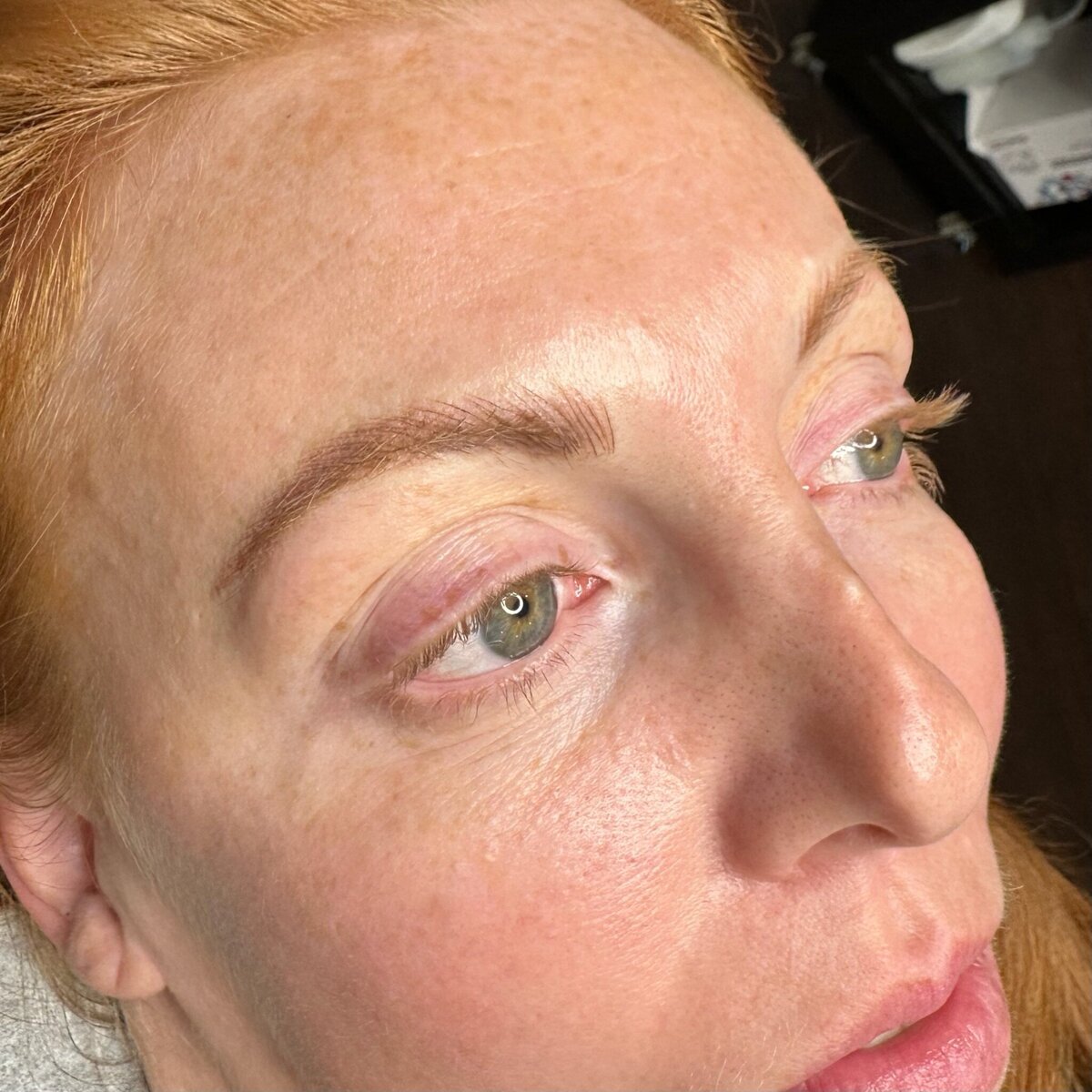 Female red-head enhanced eyebrows that look naturally fluffy, through nicroblading services at ARCHED Coastal in Gulf Shores, Alabama.