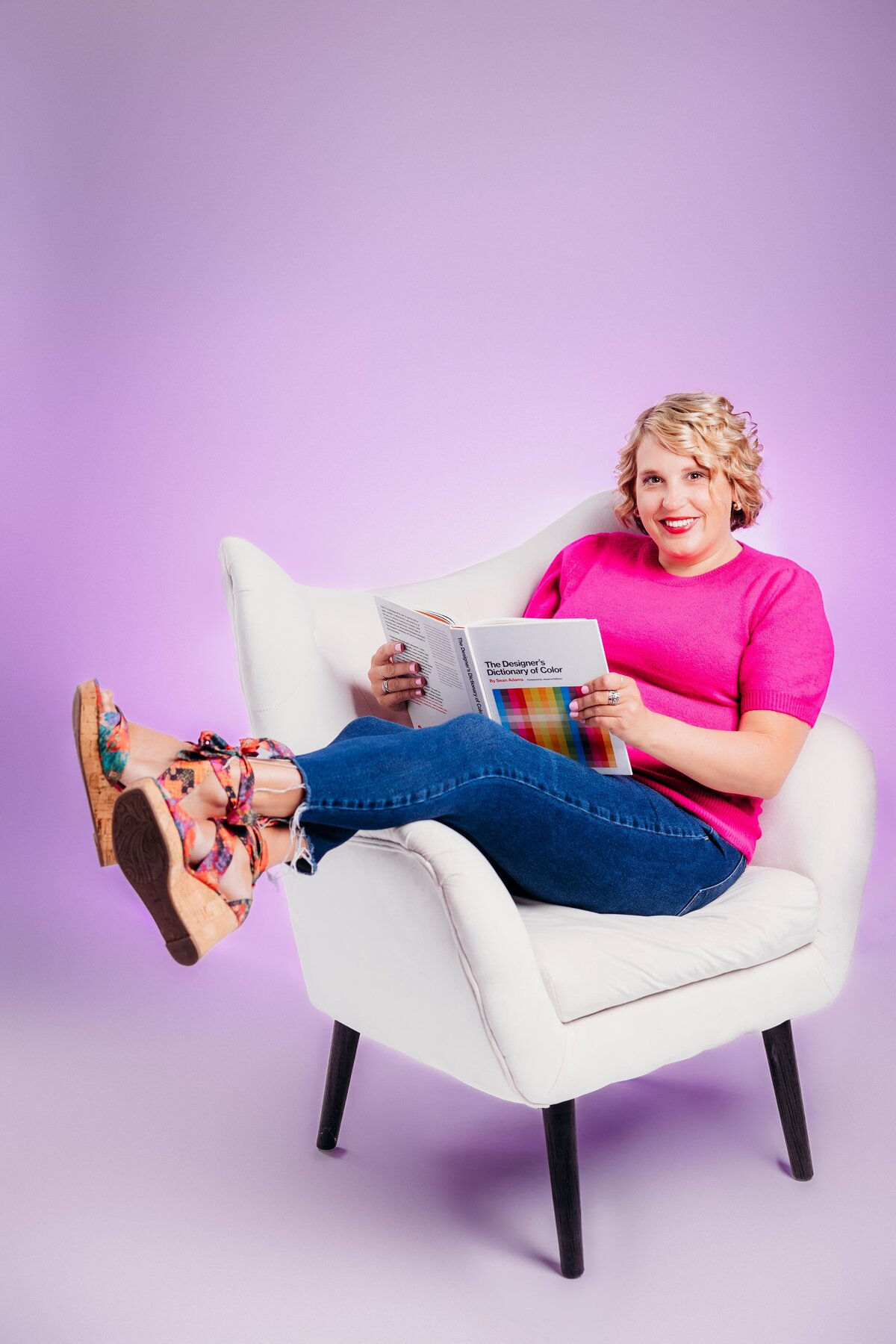Female creative sitting in a white wingback chair.