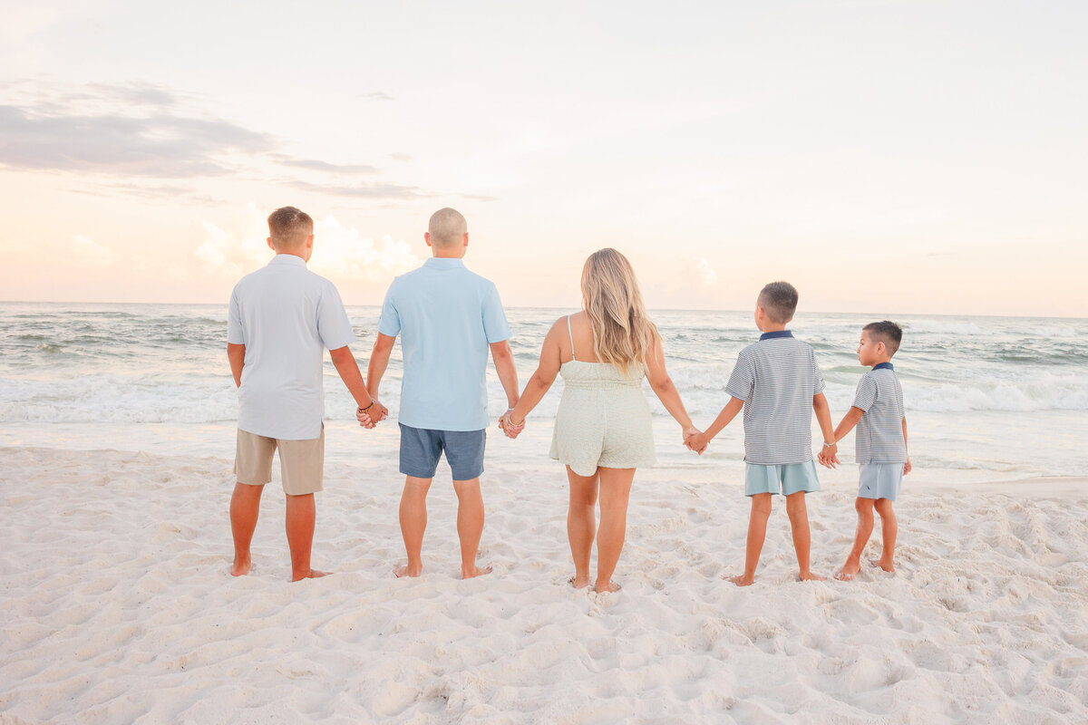Family looks at water while holding hands