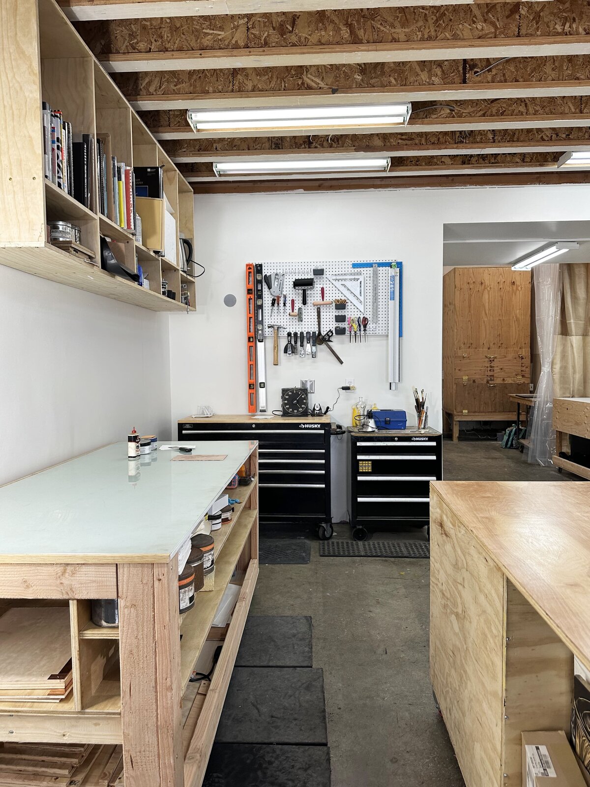 A tidy ink station with neatly arranged shelves, inks, rollers, and tools ready for the printmaking process in a studio setting.