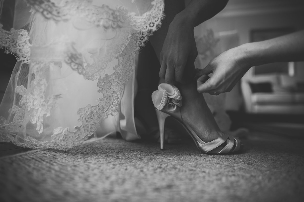 bridesmaid putting shoes on bride