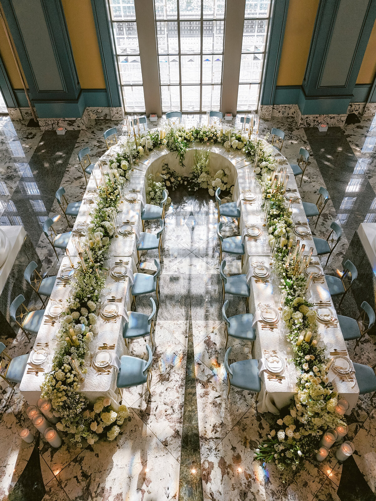custom U-shaped table for wedding party filled with white floral runner and candelabras