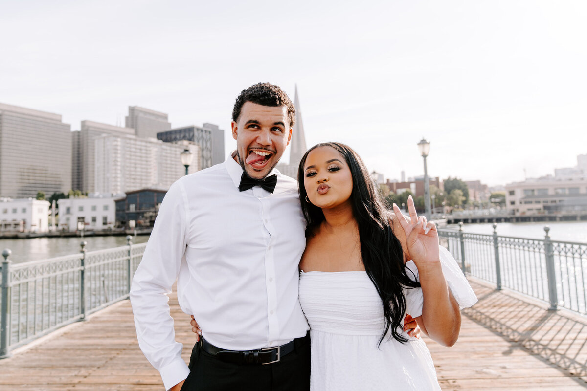 newlyweds pose silly on boardwalk