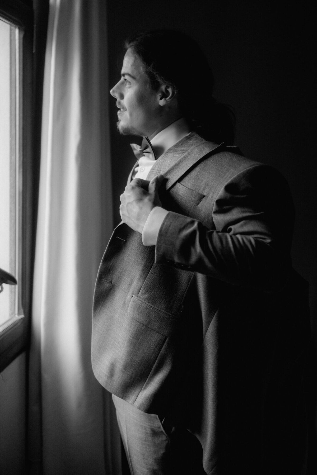Getting ready photography of groom putting on his jacket.
