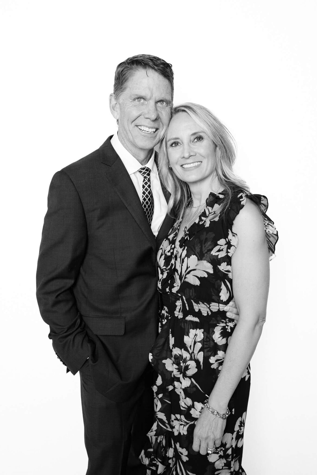 A smiling couple dressed in formal attire posing for a classic black and white portrait by Monochrome Portraits, a Phoenix photo booth experience.