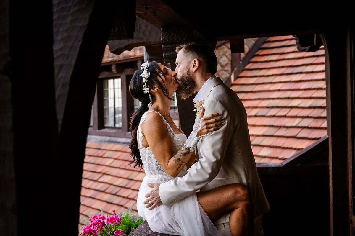 Groom kissing bride on deck at Castle in the Clouds mansion