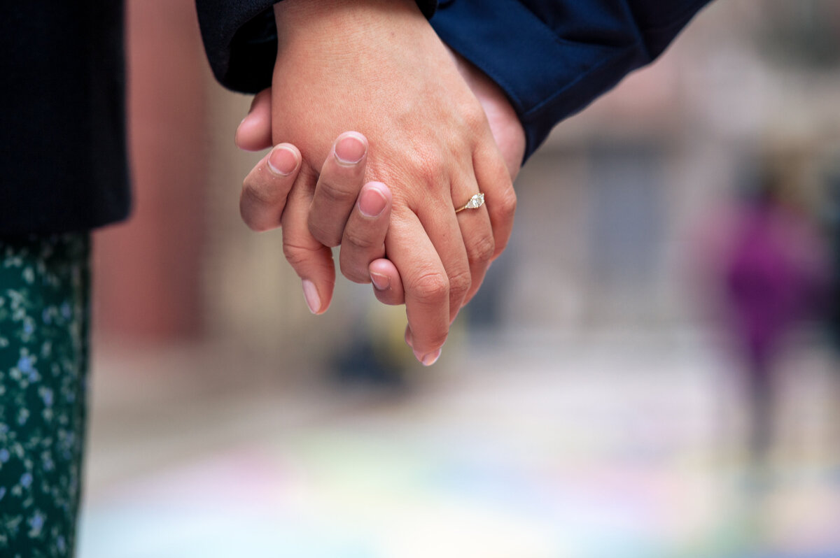 Engaged couple holding hands against the colorful NYC China town streets.