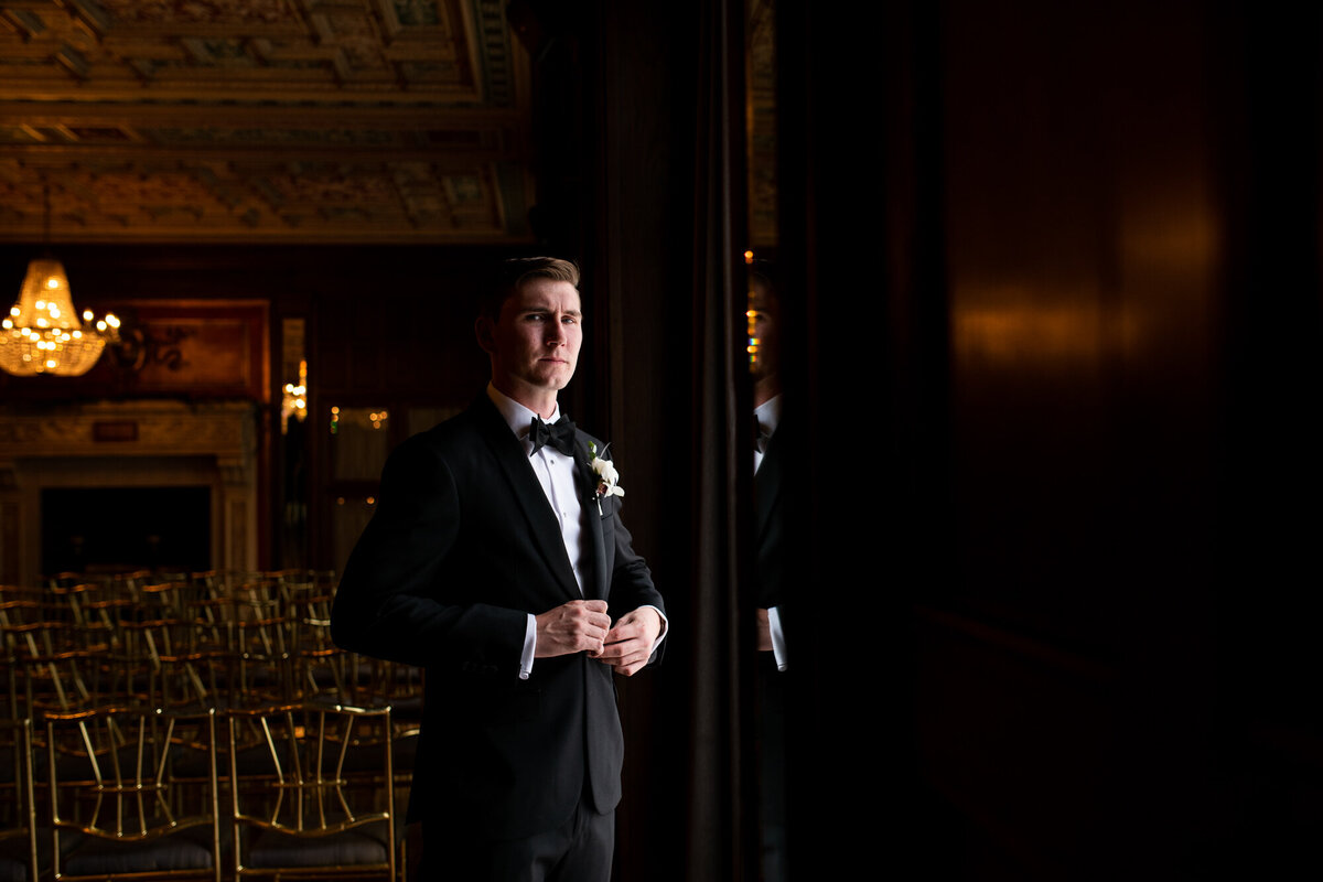 Groom adjusts jacket for portrait at The Athletic Club of Columbus