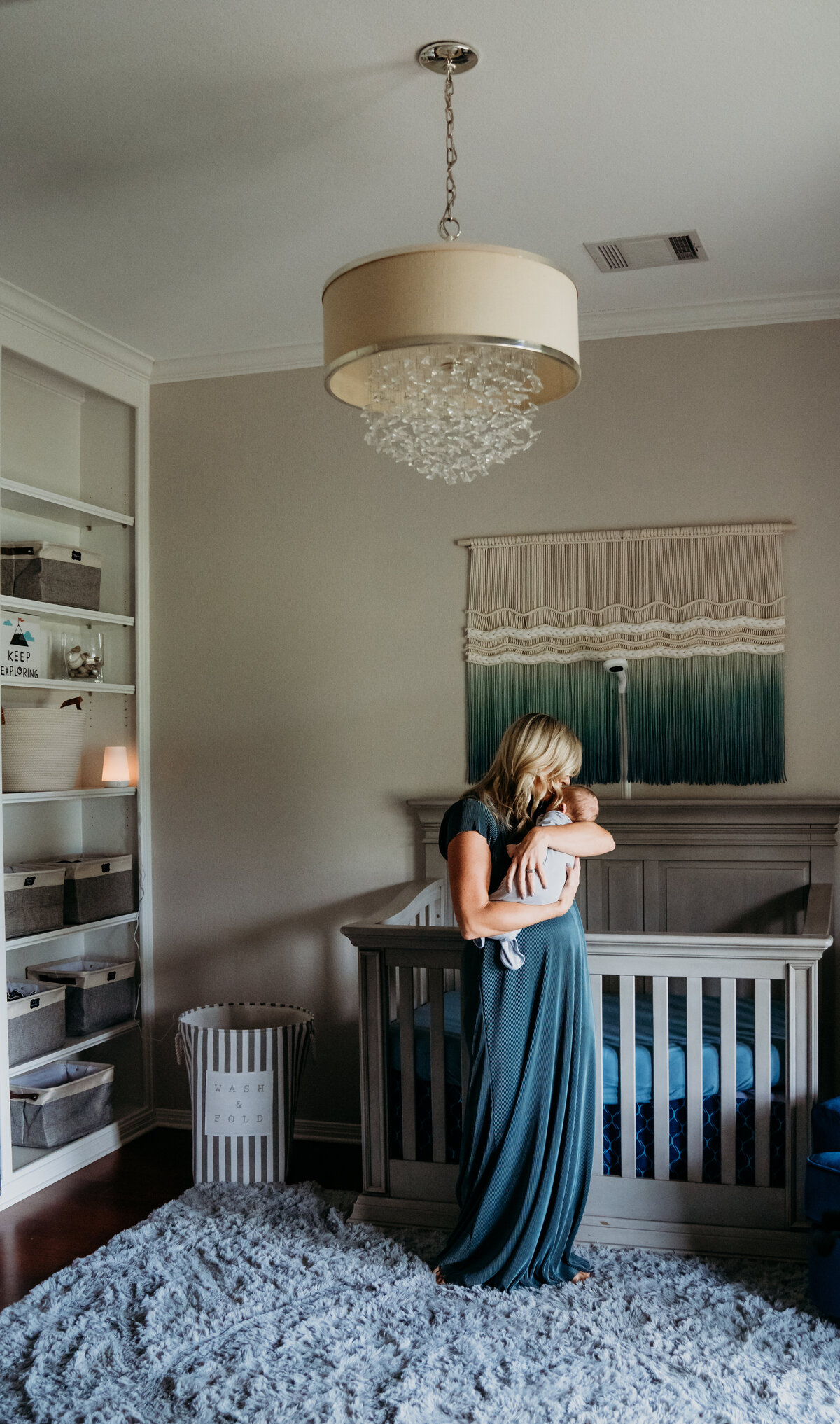 Newborn Photographer, a mother stands in the nursery holding her baby