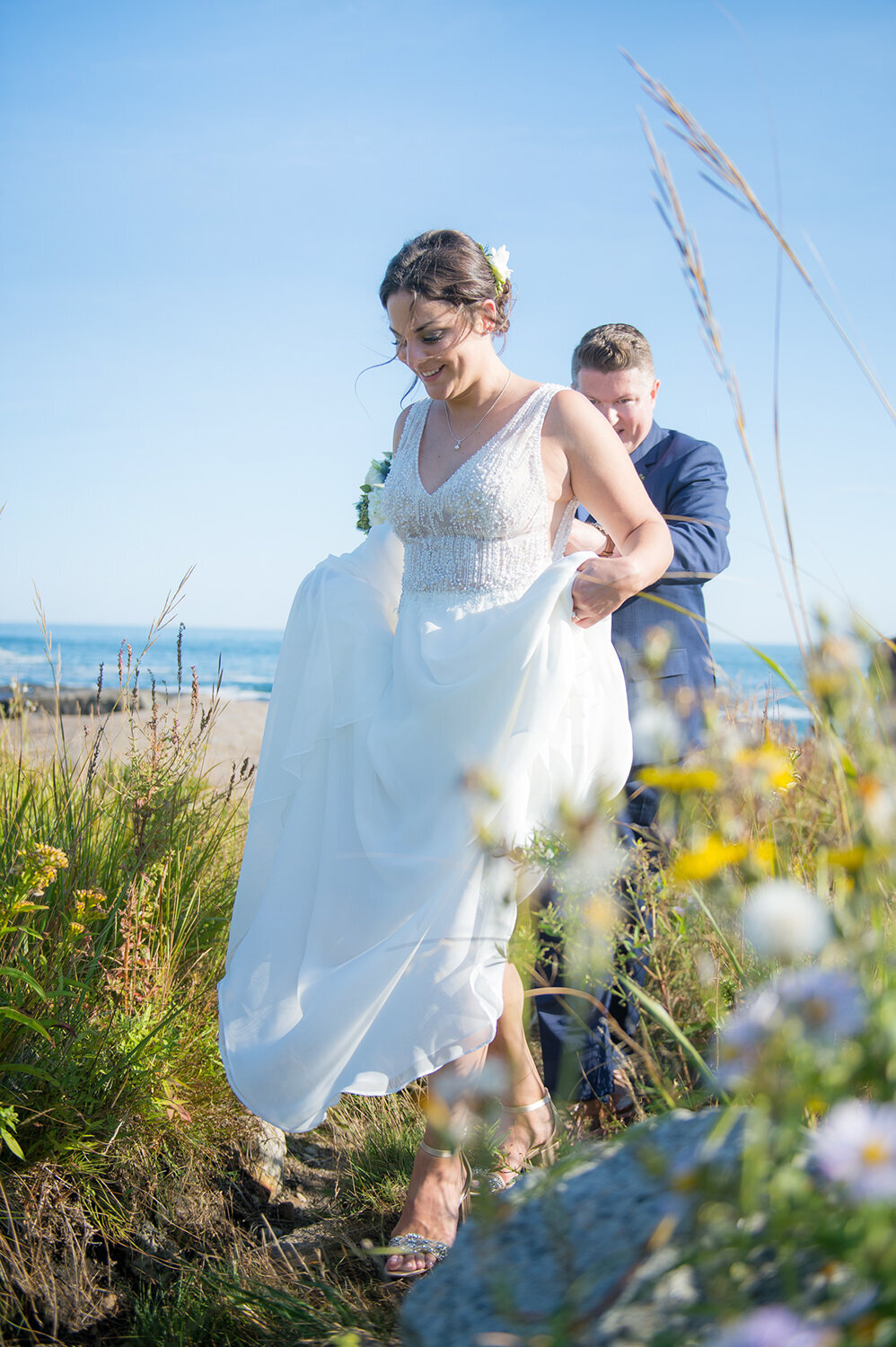 Bride and Groom walking on grassy path at Nubble Lighthouse in York Maine