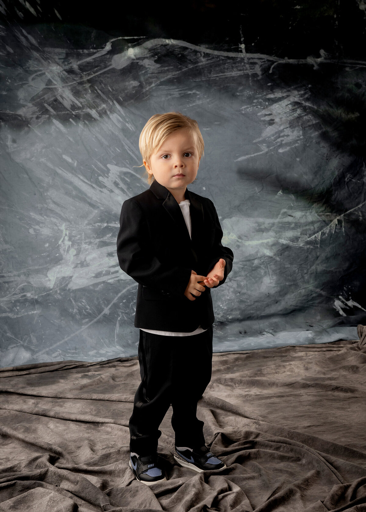 Toddler boy stands looking serious in a studio