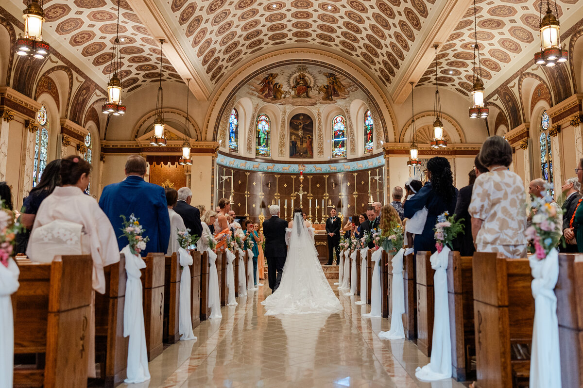 A photograph of a bride walking down the aisle of a church.
