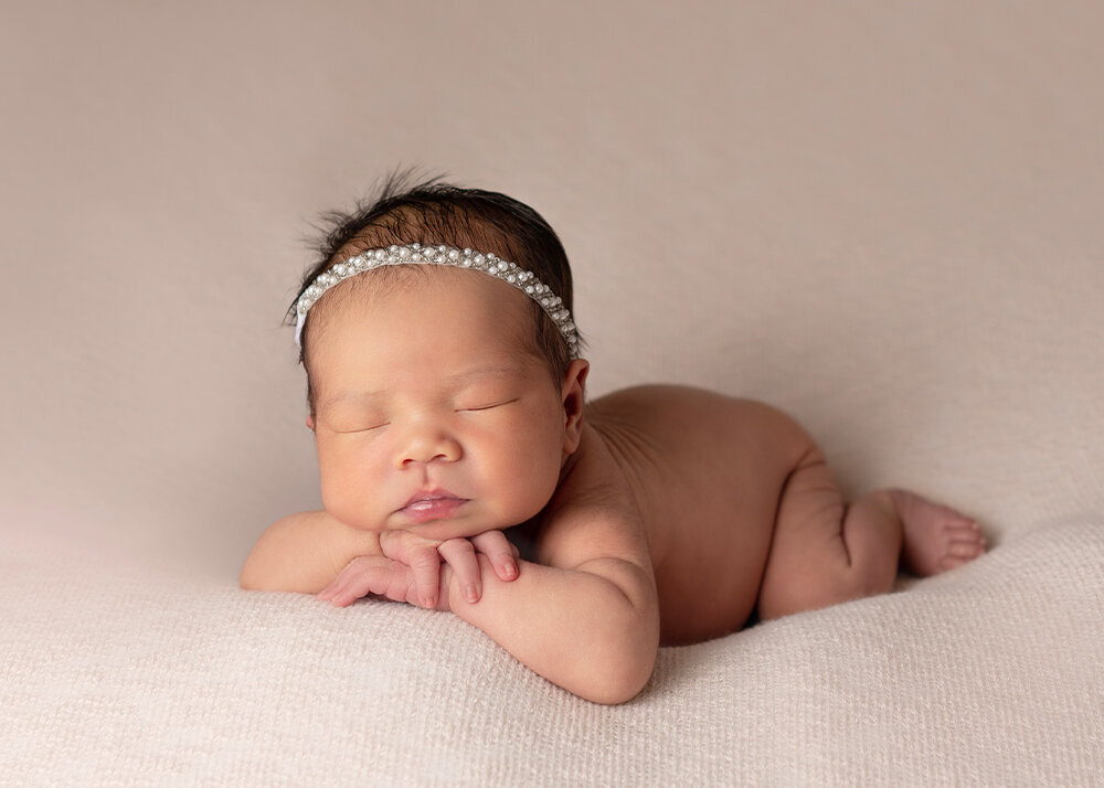 newborn-girl-on-pink-blanket-with-chin-on-hands