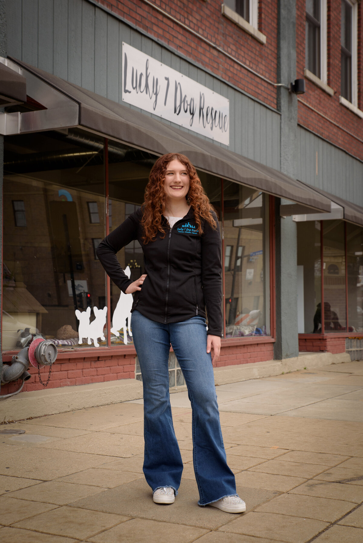 Green Bay East High School senior girl with red curly hair at Lucky Seven dog rescue in urban setting in downtown Green Bay, Wisconsin.  Animal lover.