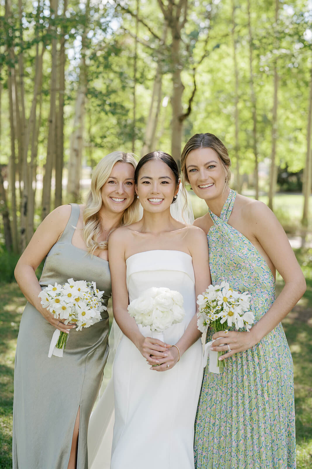 Bride poses alongside two bridesmaids among a grove of beautiful aspen trees at the Aspen Meadows Resort wedding.