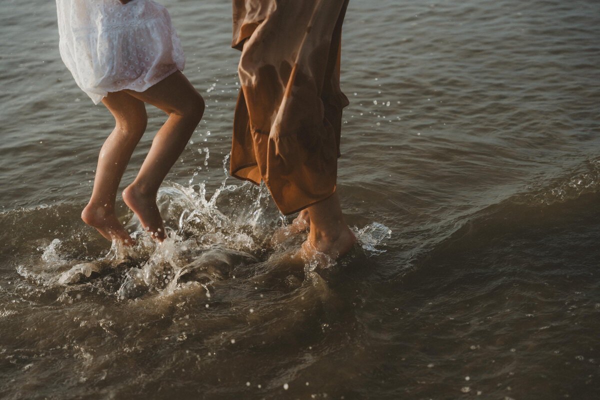 Detailfoto van moeder en zoon die spelen met hun voeten in de zee.
