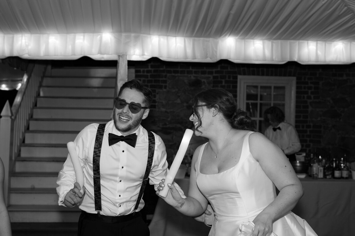 Newlyweds singing into foam sticks during their wedding reception