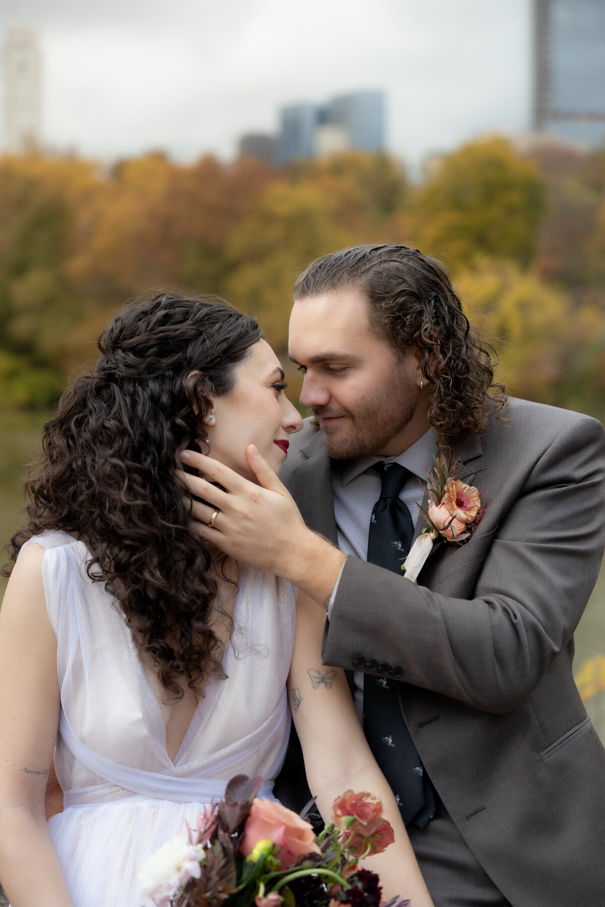 The couple standing close together surrounded by Central Park’s glowing fall foliage.