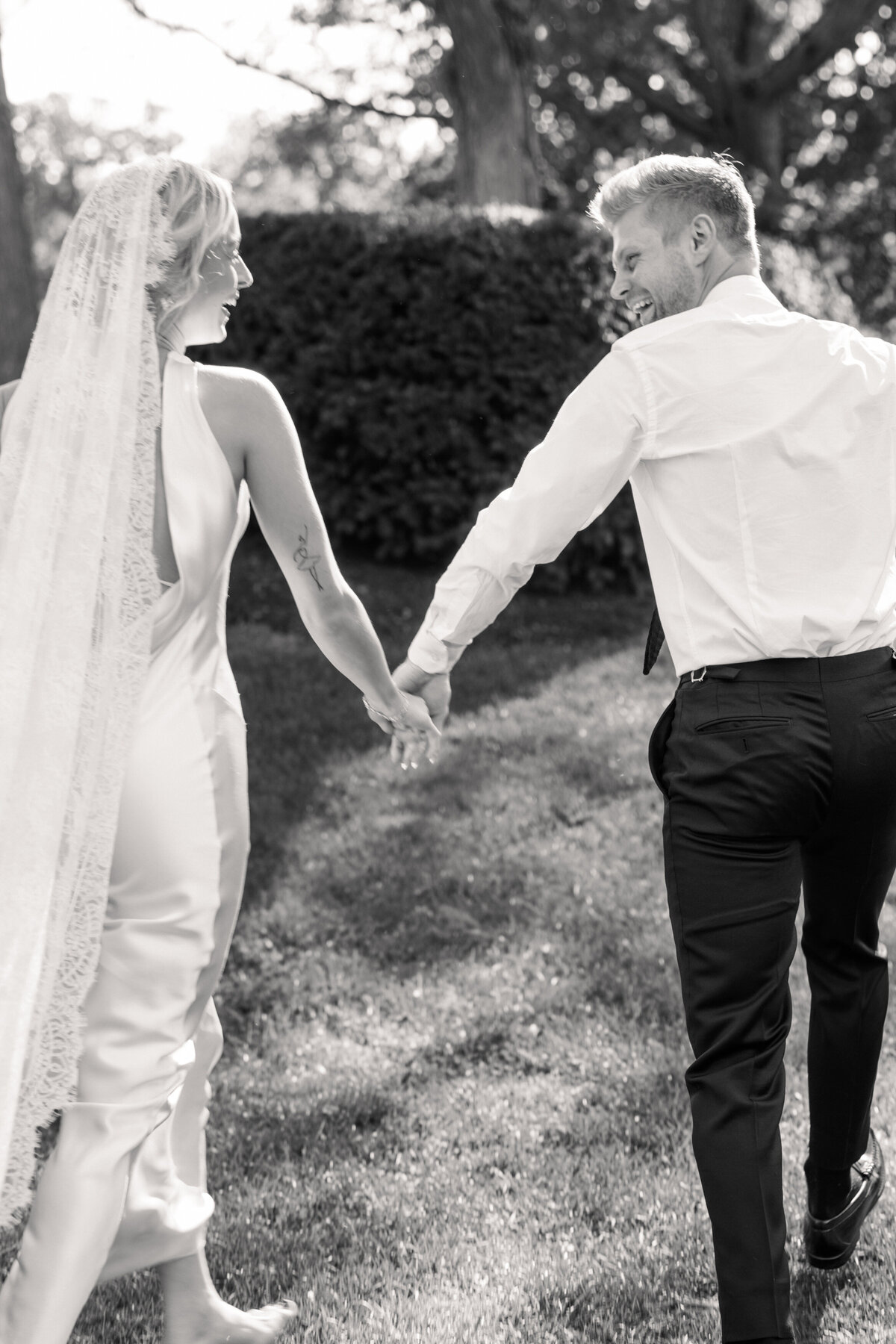 Groom and bride holding hands, laughing during Dayton, Ohio wedding, captured by Philadelphia wedding photographer.