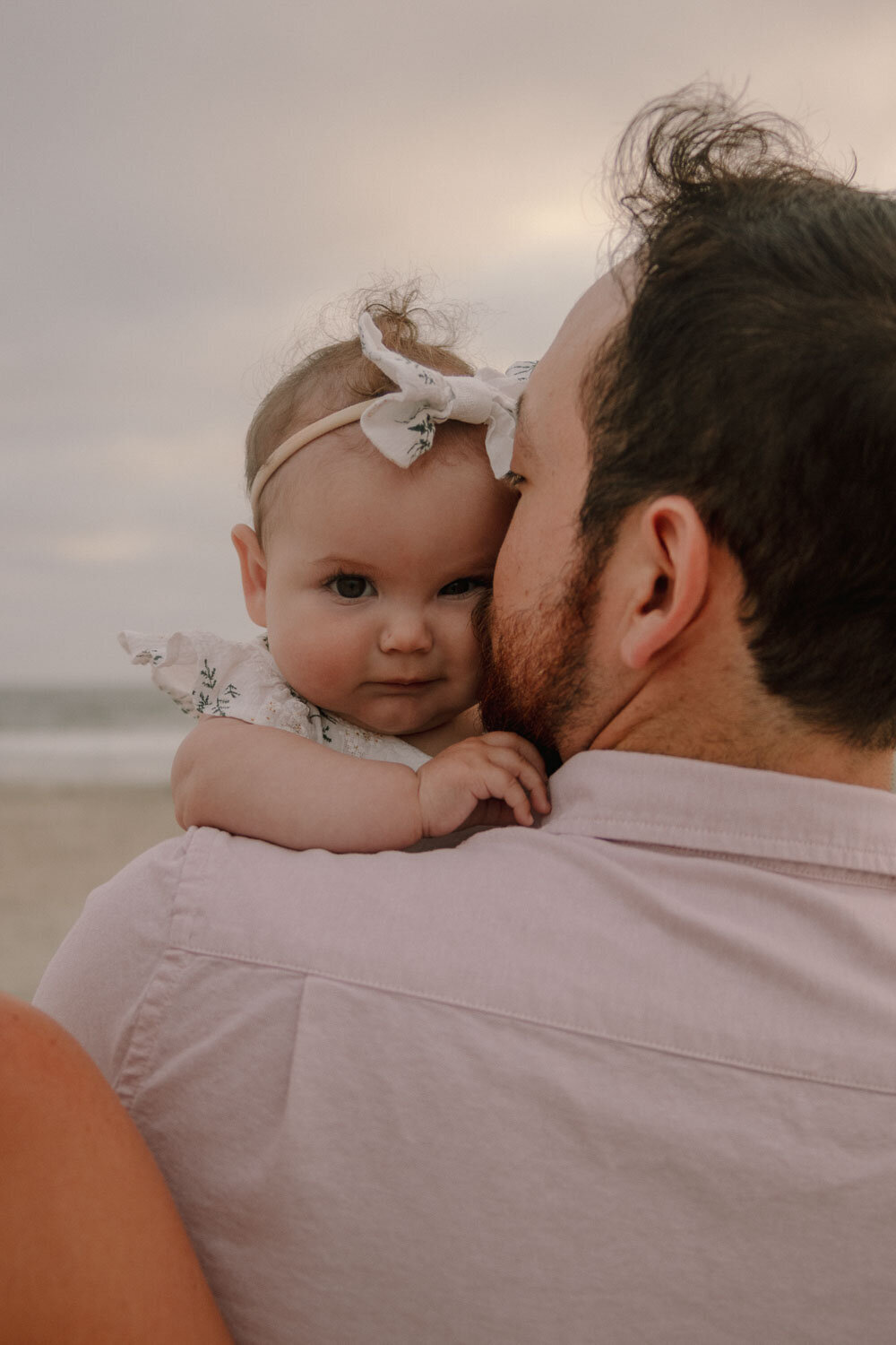 Father holding his baby close, looking back at the camera