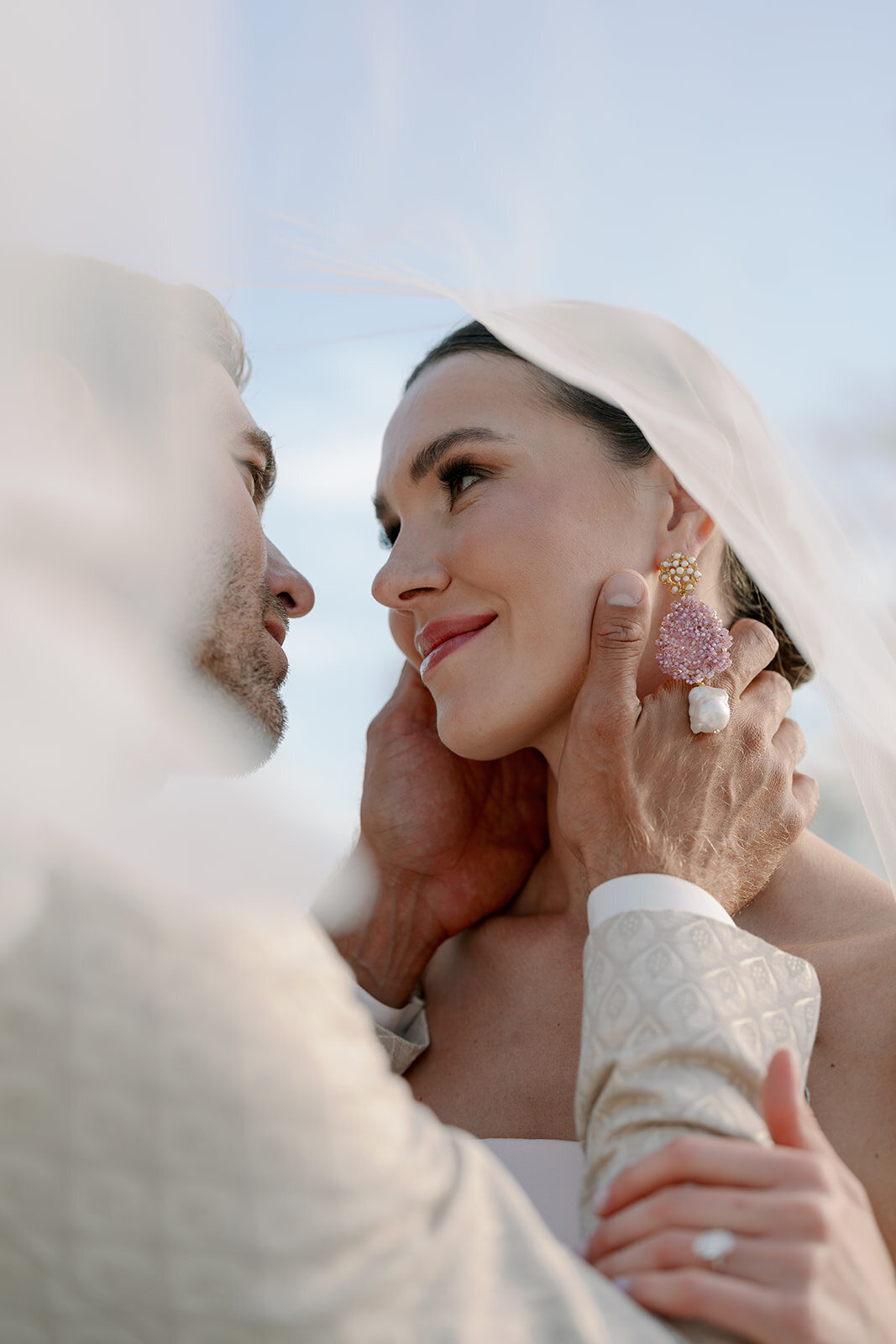 Bride and groom embracing closely under sheer veil during romantic wedding portraits at Château de Tourreau.