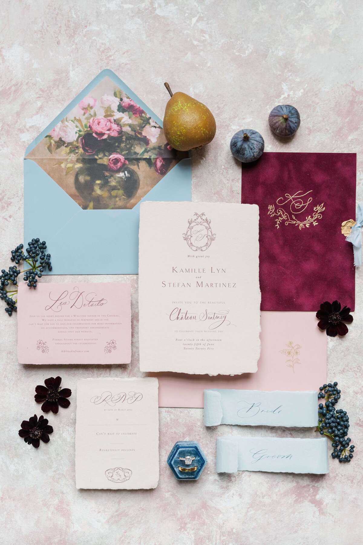 flatlay of wedding invitations with the rings, envalopes, fruits and flowers