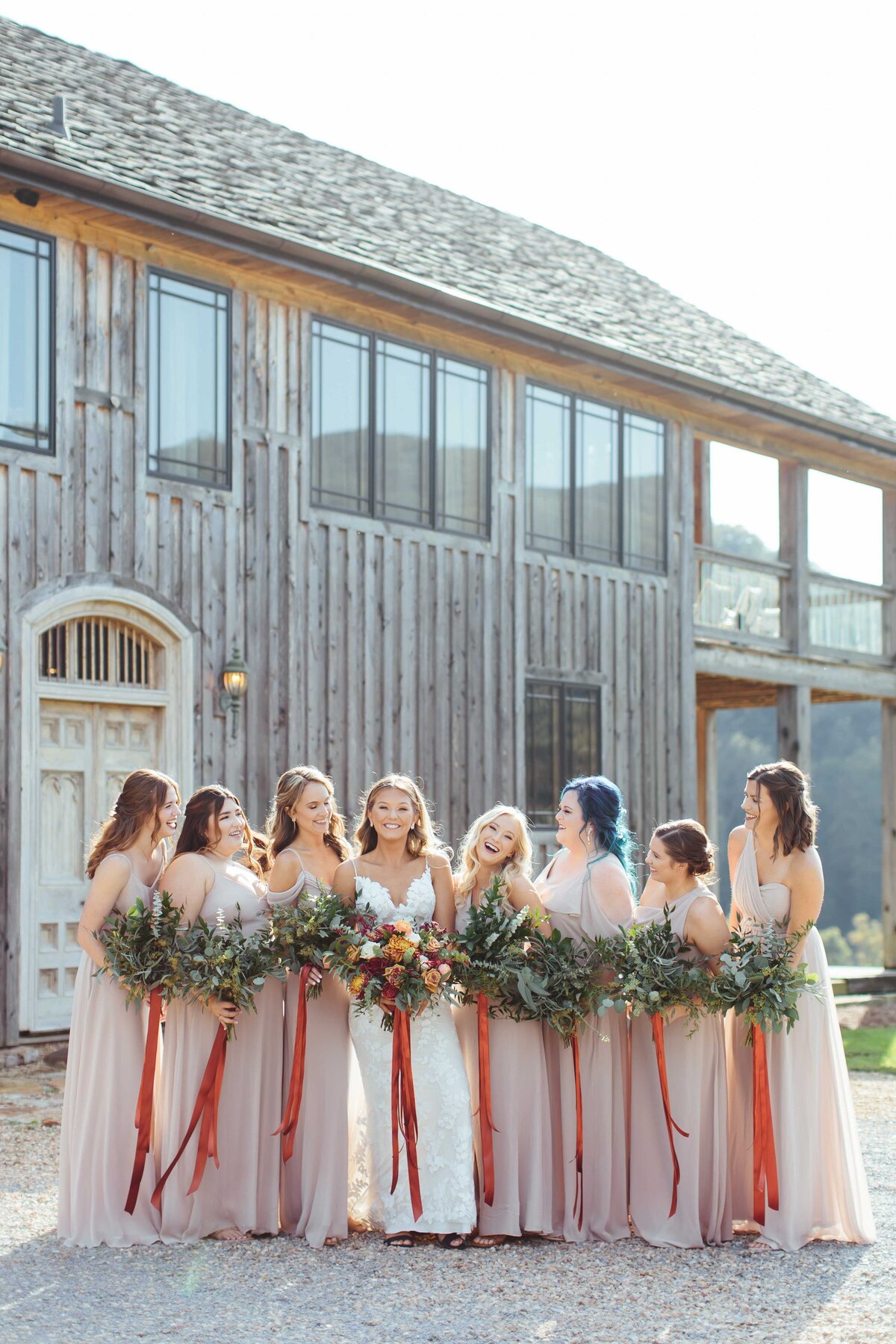 Bridesmaids giving bride all the attention with crooked river venue in background