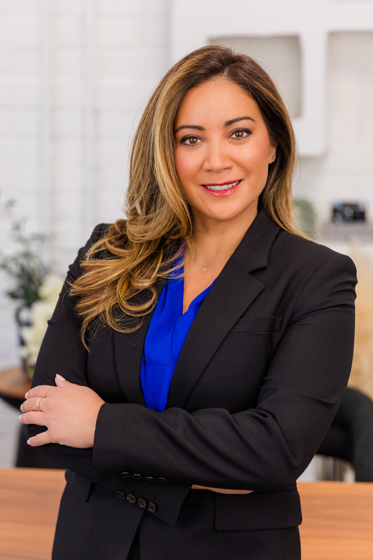 woman with long hair wearing corporate outfit blue top and black jacket standing arms crossed in an office Atlanta headshot Laure Photography