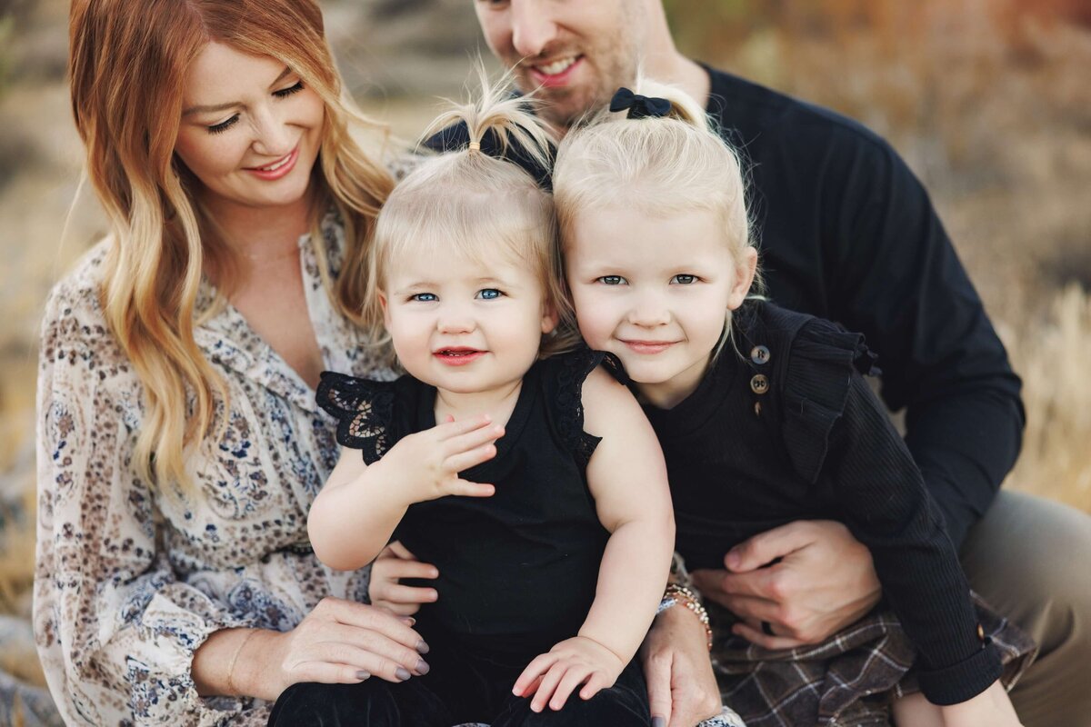 Young family with two girls snuggles together.