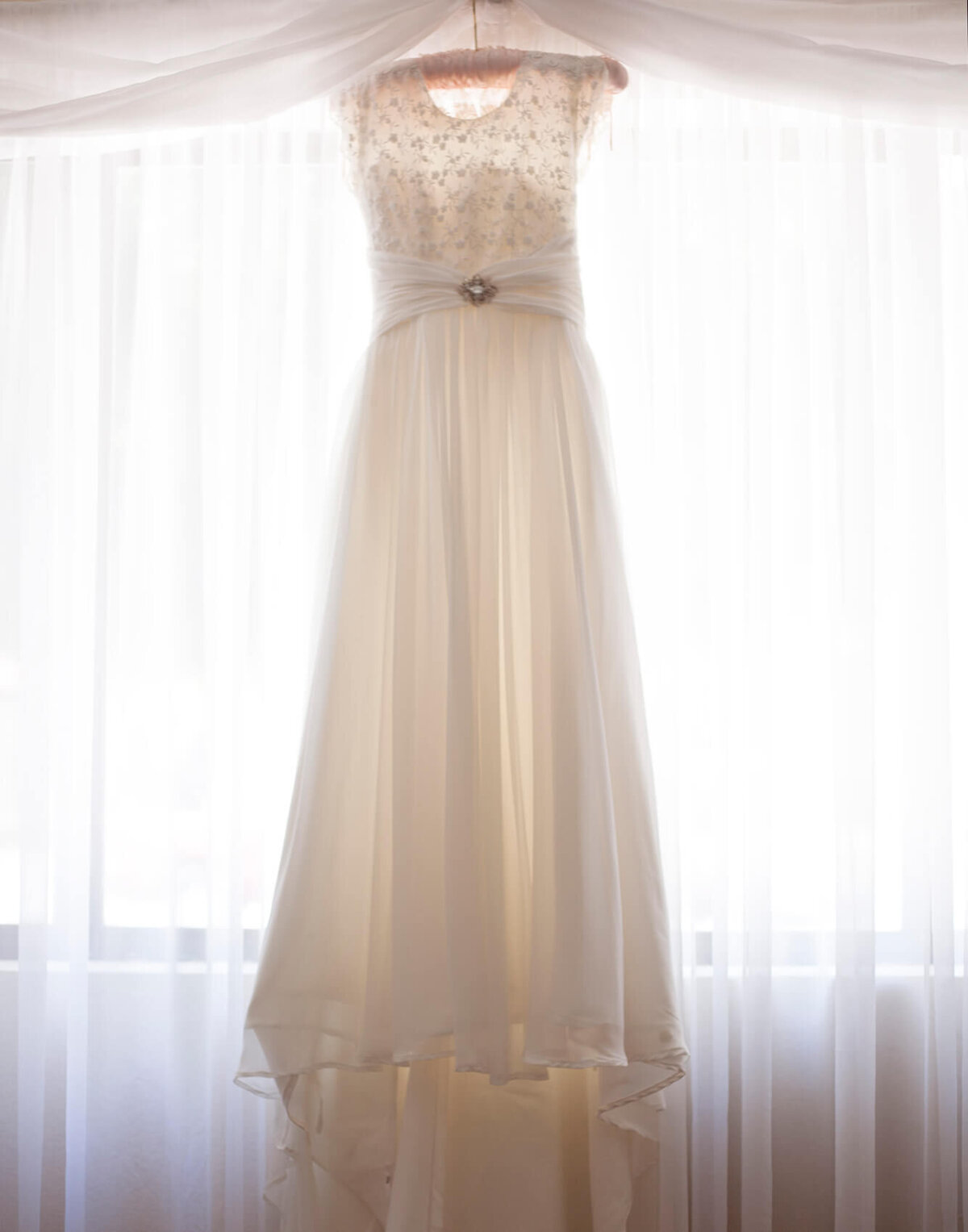 a short sleeved wedding dress hanging on a window