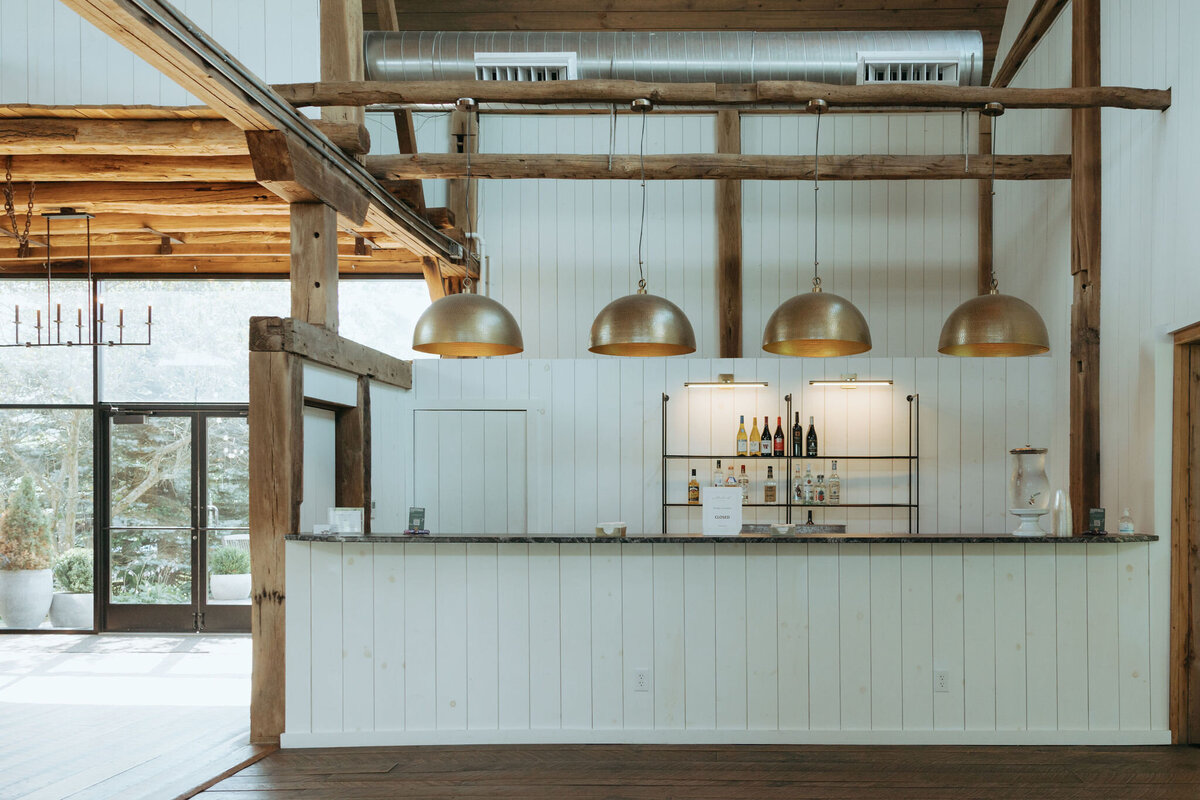 The full service bar with hammered brass Crate and Barrel pendant lights at Willowbrook wedding venue