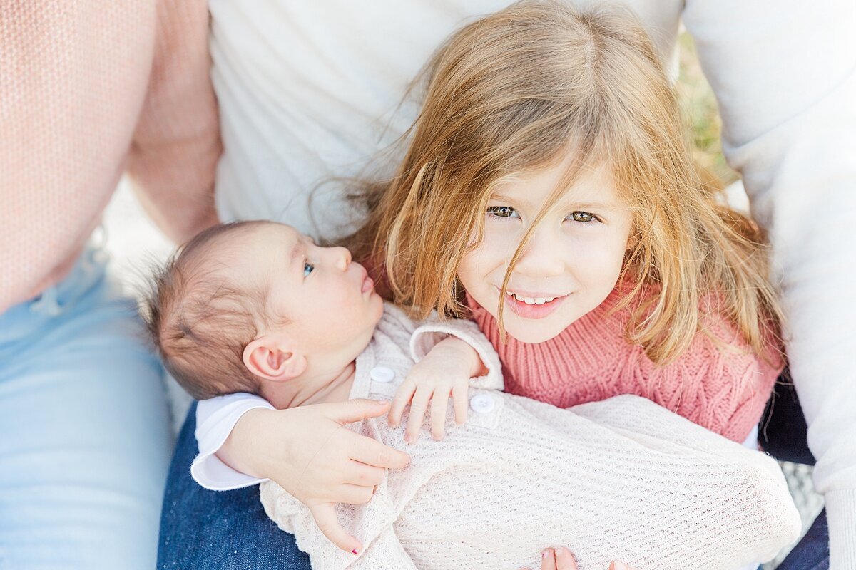 girl holds baby during outdoor newborn photo session with Sara Sniderman Photography