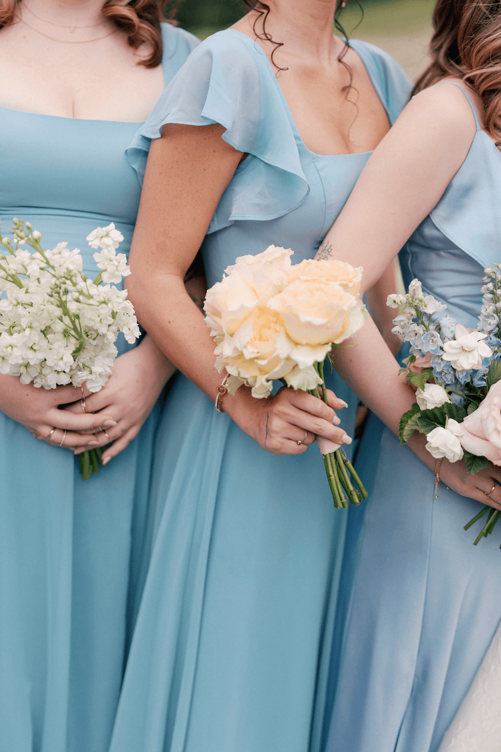 Close-up of bridesmaids in soft blue dresses holding pastel bouquets at a summer wedding at Moonlight Basin.